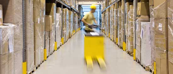 A forklift driver speeds down a warehouse aisle to retrieve an order.