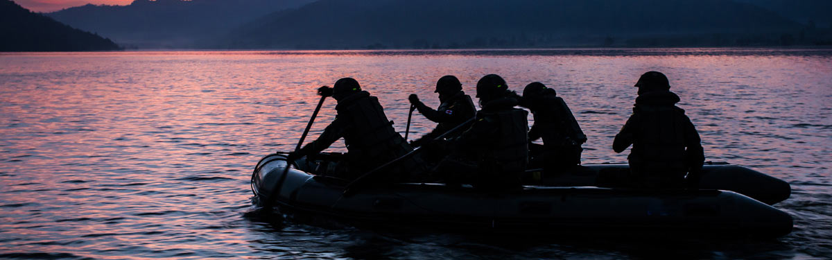 Military SEALS paddle an inflatable past a Washington State island on maneuvers.