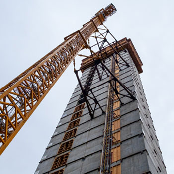 A construction crane next to a highrise under construction in downtown Seattle.