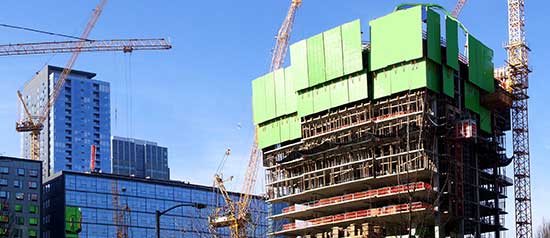 A building surrounded by construction cranes is built in downtown Seattle