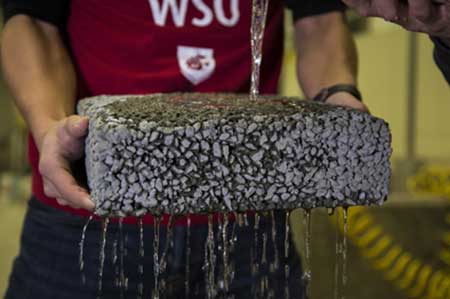 A researcher at Washington State University holds a sample of permeable, carbon fiber infused concrete that lets water drain naturally.