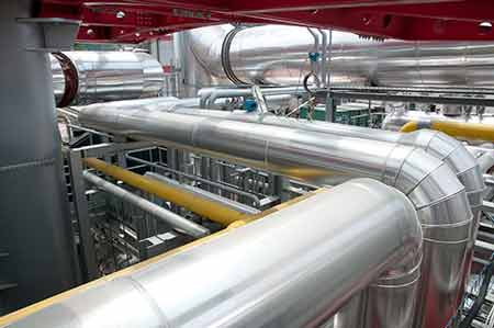 Interior of a pulp mill showing the network of pipes used to process raw materials into pulp.