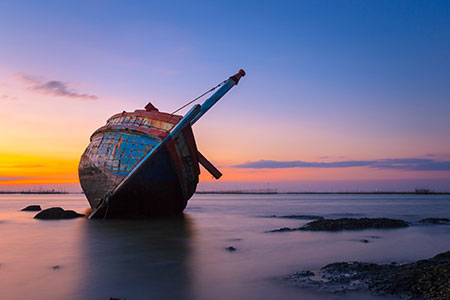 A derelict boat aground on a beach awaits recycling in a new Washington State program.