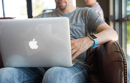 A young man works on an Apple Mac Air in a cafe.