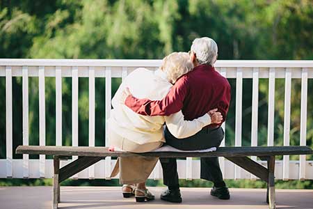 An elderly couple on a park bench enjoy their retirement years.