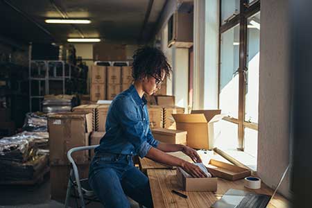 A small business owner prepares an ecommerce order for shipment.