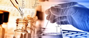 A researcher holds a flask and a dropper in front of the Periodic Table of Elements